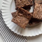 homemade brownie squares on a white plate with a black and white striped napkin