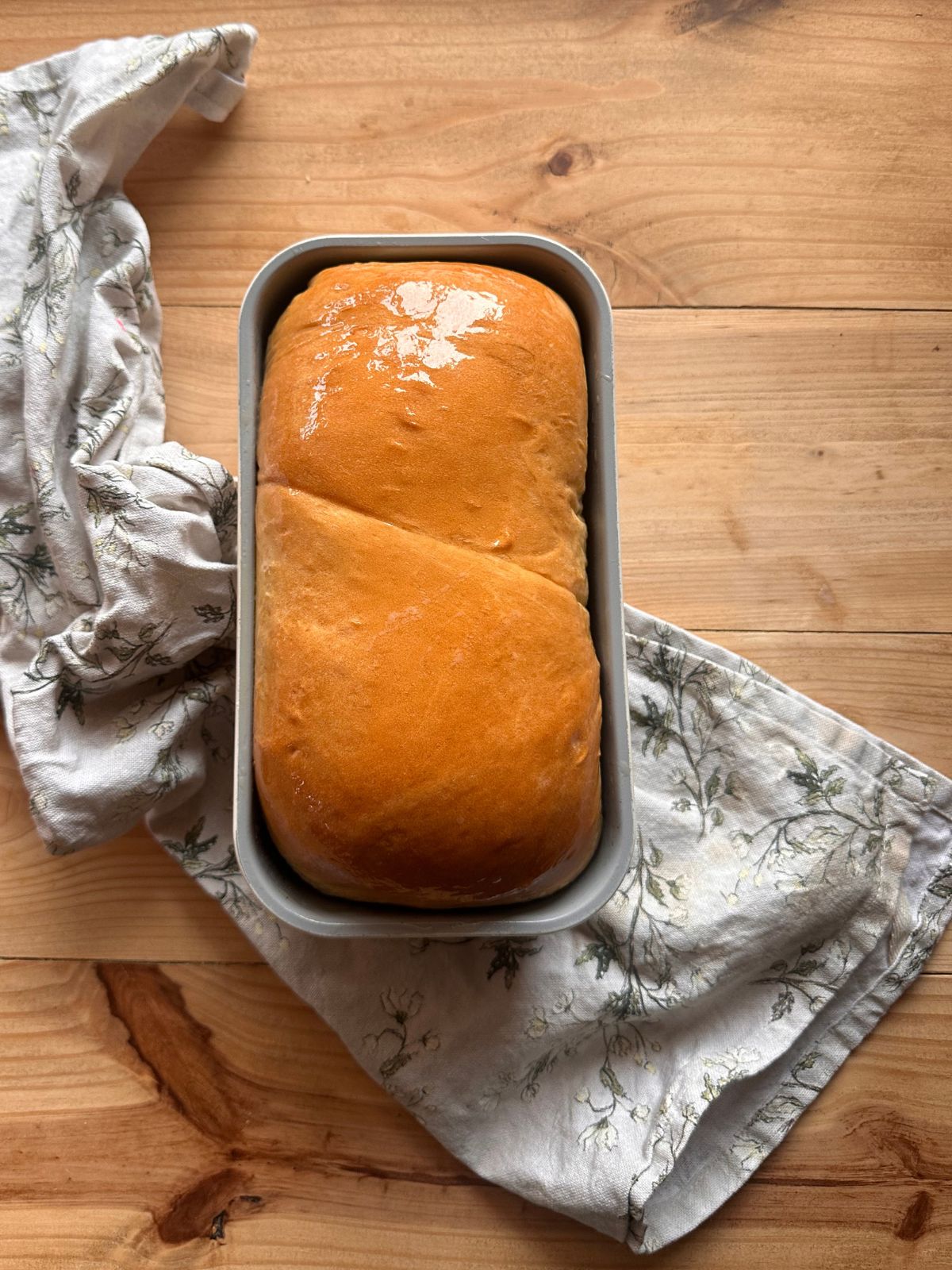 a loaf of baked sandwich bread, sitting on a wooden countertop