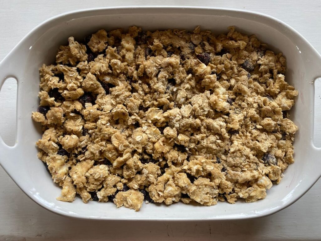a large white baking dish of blueberries, topped with a brown sugar crumble