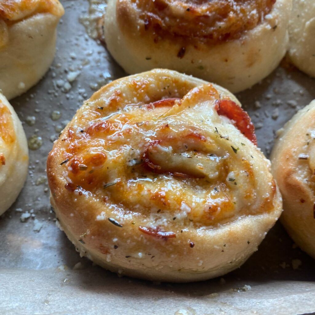 a close up view of a homemade pepperoni pizza roll, topped with garlic butter and sprinkled with Parmesan cheese