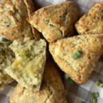 cheddar scones with fresh herbs on a brown and white checkered towel
