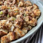 A pan of baked sourdough bread stuffing with sausage, sauteed veggies, and herbs