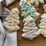 Sourdough sugar cookies cut into Christmas tree shapes, drizzled with icing and sprinkles