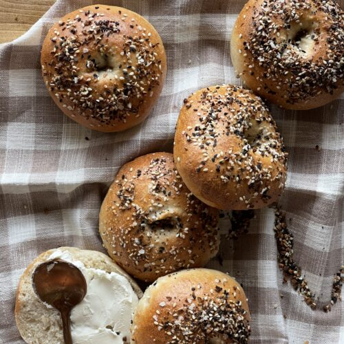 sourdough bagels seasoned with everything seasoning laying on a checkered towel