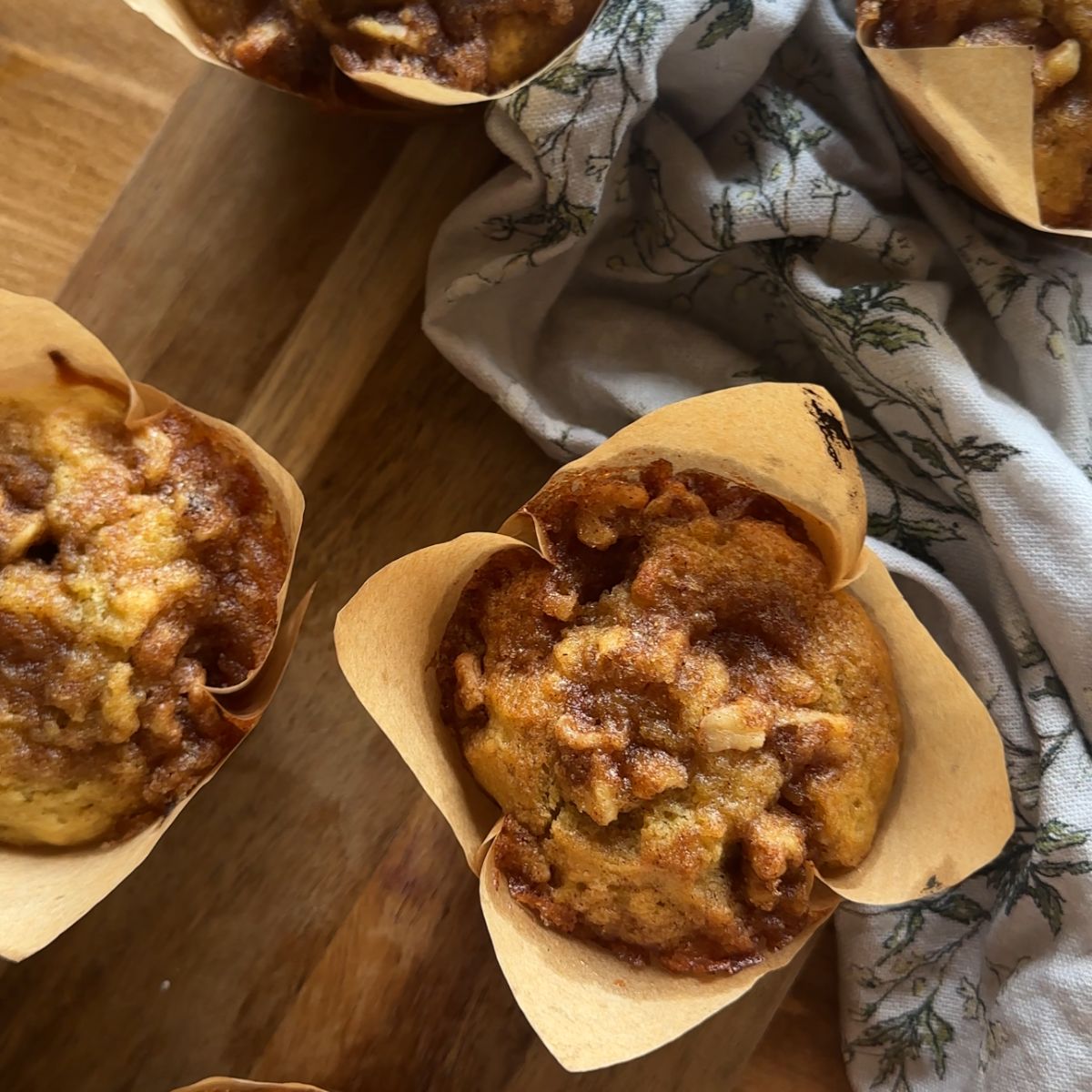 sourdough banana muffins arranged on a wooden cutting board, with a floral towel lying in the background