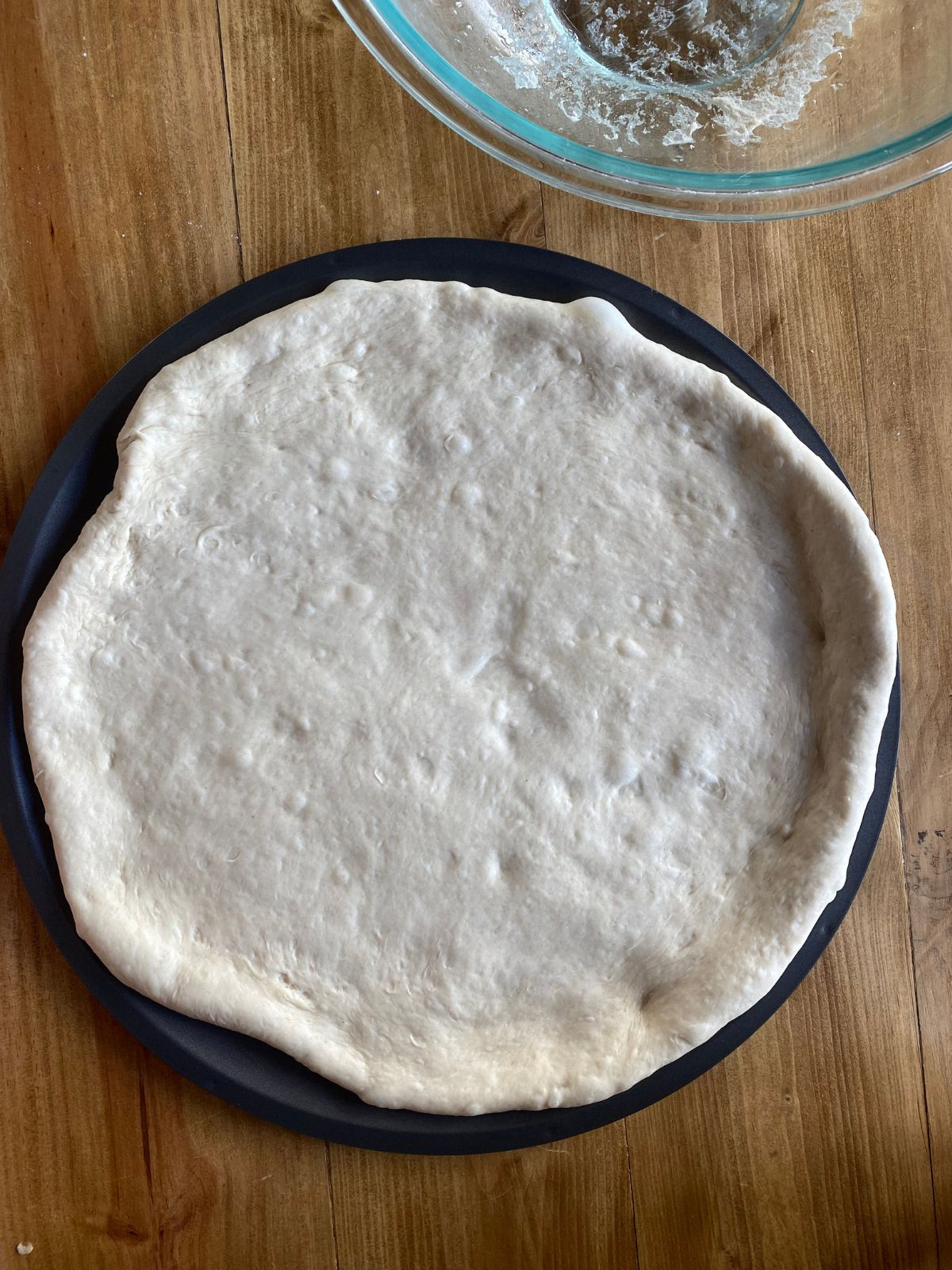 pizza dough spread onto a large pizza pan