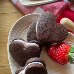 heart shaped chocolate sandwich cookies filled with strawberry frosting on a pink plate