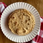 whole grain tortillas stacked on a white plate with a red and white checkered towel underneath