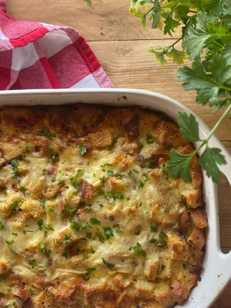 bacon and cheddar sourdough breakfast casserole baked in a white casserole dish