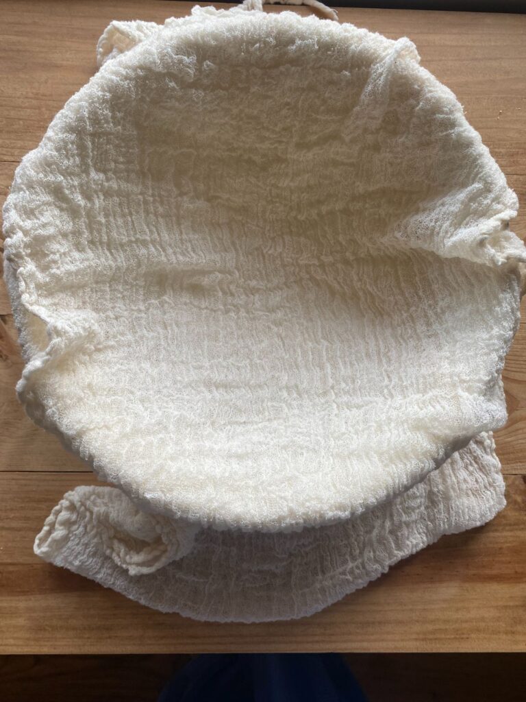 A large mixing bowl covered with cheesecloth