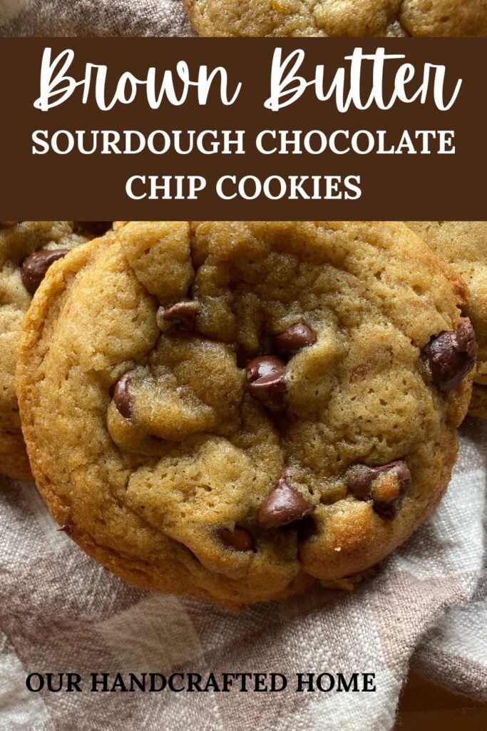 a close up view of a baked sourdough chocolate chip cookie laying on a checkered towel. Text overlay reads "Brown Butter Sourdough Chocolate Chip Cookies"