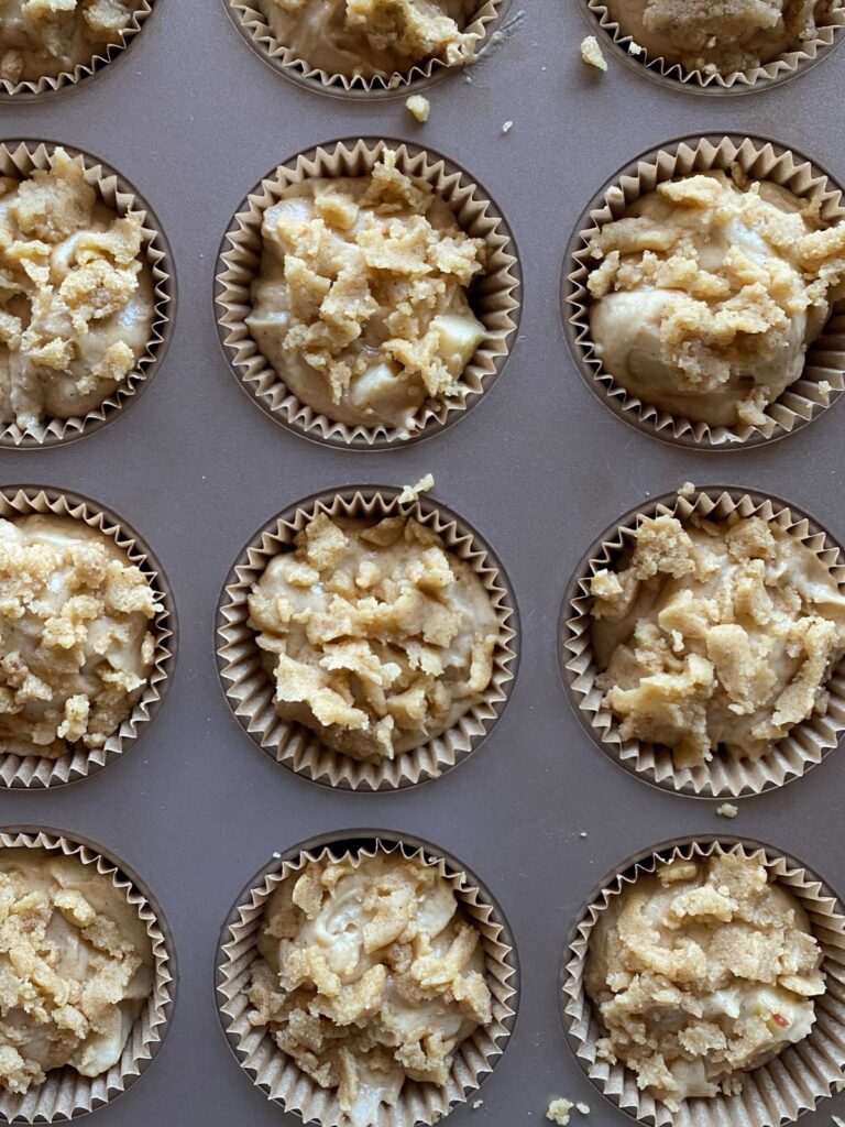 unbaked sourdough apple muffins in a muffin tin topped with a crumble topping