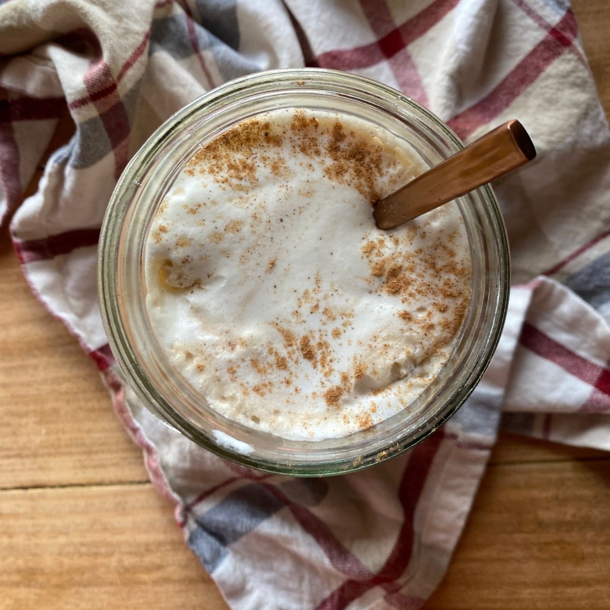 Top down view of homemade pumpkin pie spice coffee creamer in a glass jar, with cinnamon sprinkled on top