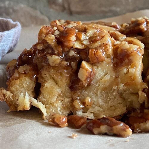 Close-up of homemade sourdough sticky buns topped with caramelized pecans and rich cinnamon glaze.