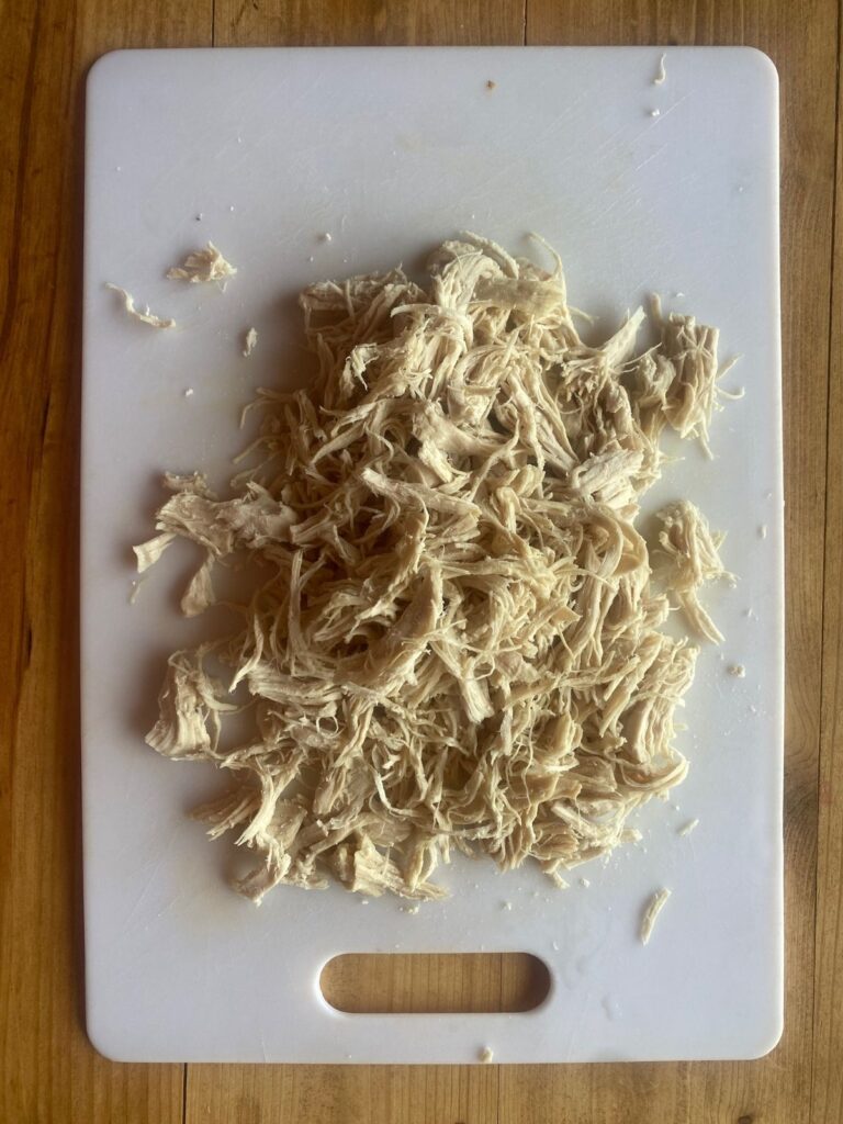 shredded chicken on a white cutting board