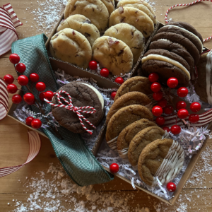 A festive Christmas cookie box filled with a variety of Christmas cookies, along with red berries and red and white striped ribbon