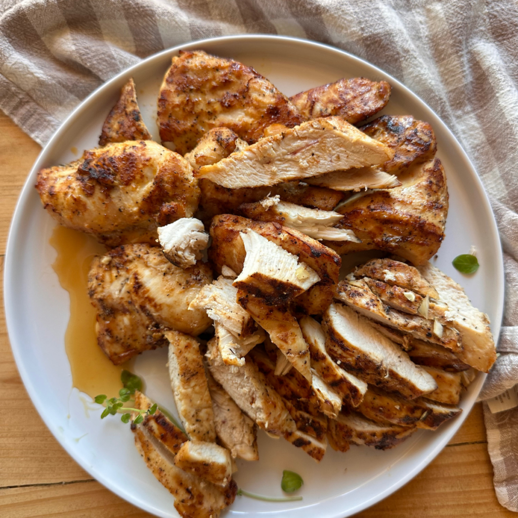Seasoned air fryer chicken breast is sliced and arranged on a white dinner plate