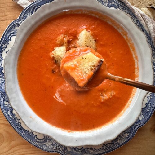 a bowl of creamy tomato soup, topped with toasted sourdough breadcrumbs