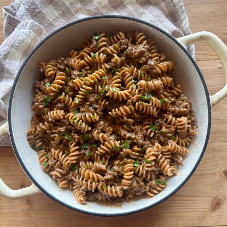 a large white baking dish full of homemade hamburger helper, topped with chopped parsley