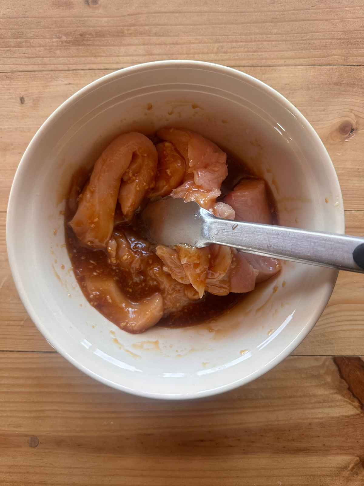 chicken tenders and honey garlic sauce, being tossed together in a large mixing bowl