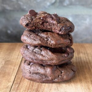 a close up view of a stack of sourdough chocolate cookies, with a bite taken out of the top cookie