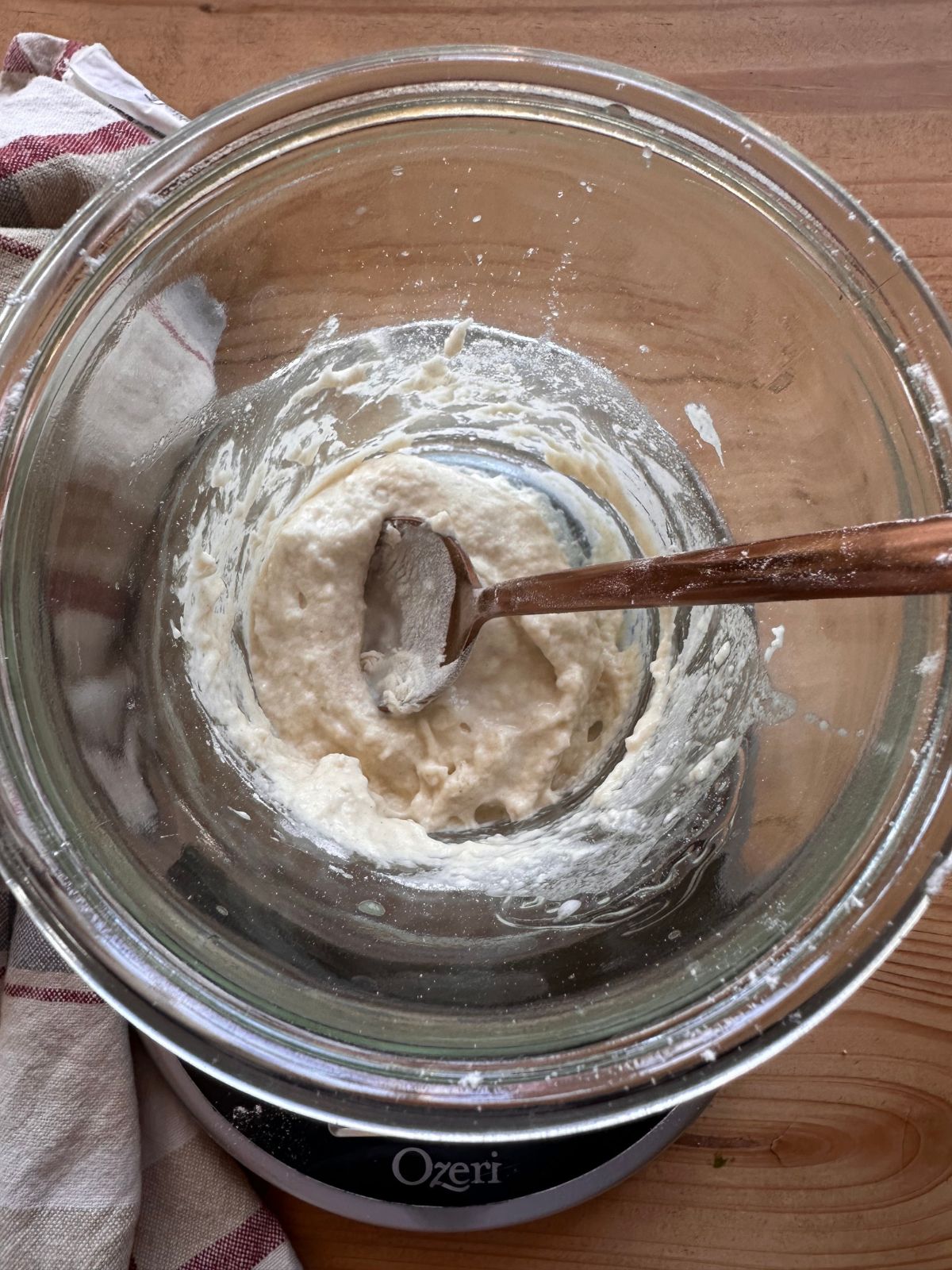 flour and water is being mixed together with a spoon, forming a thick paste for a sourdough starter