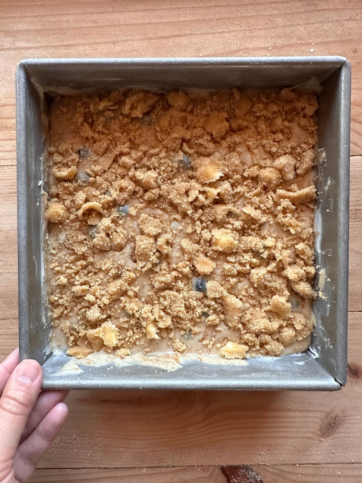 unbaked sourdough blueberry coffee cake in a square baking pan, topped with a brown sugar crumble topping