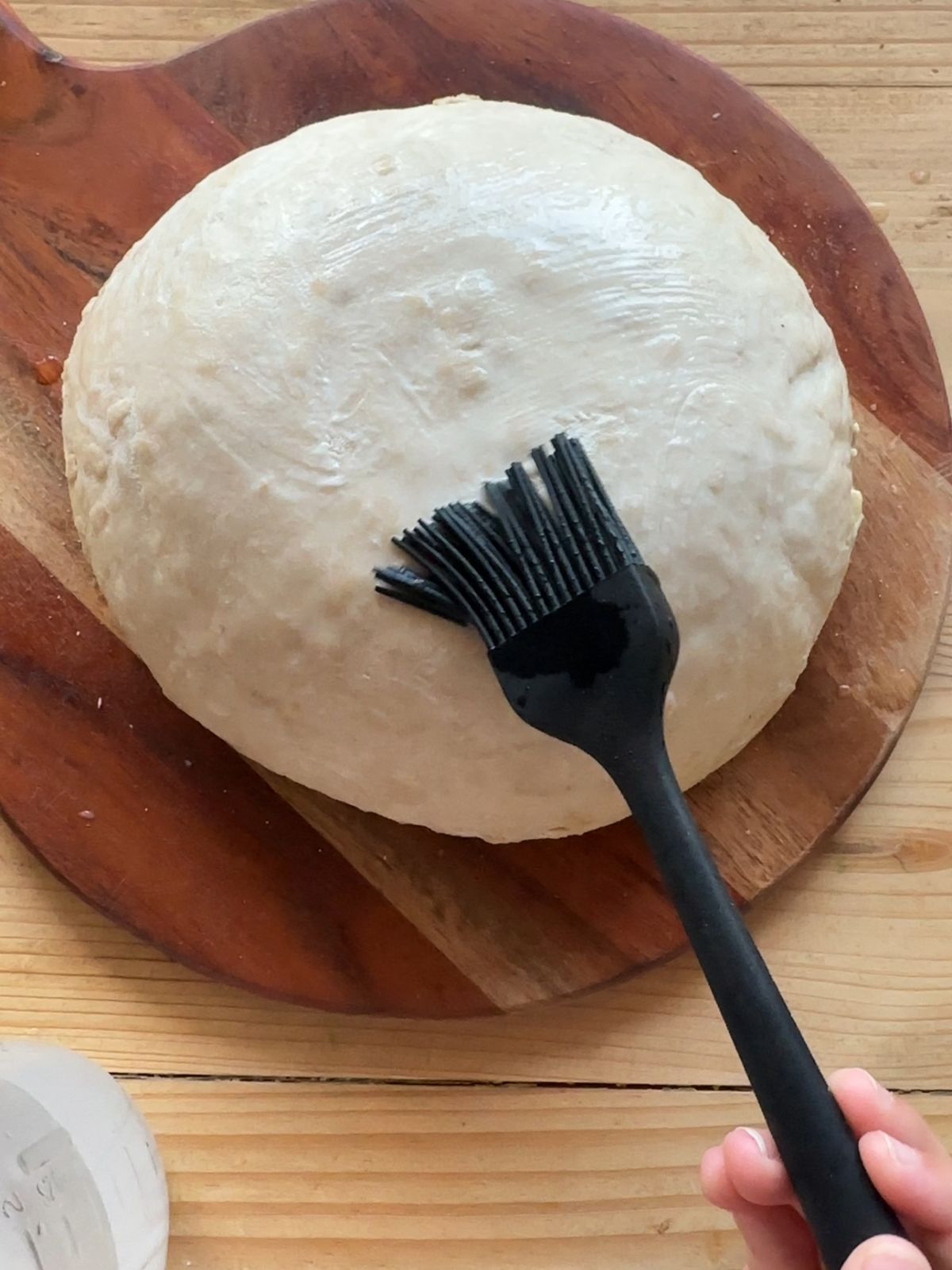 a loaf of unbacked sourdough bread being brushed lightly with water