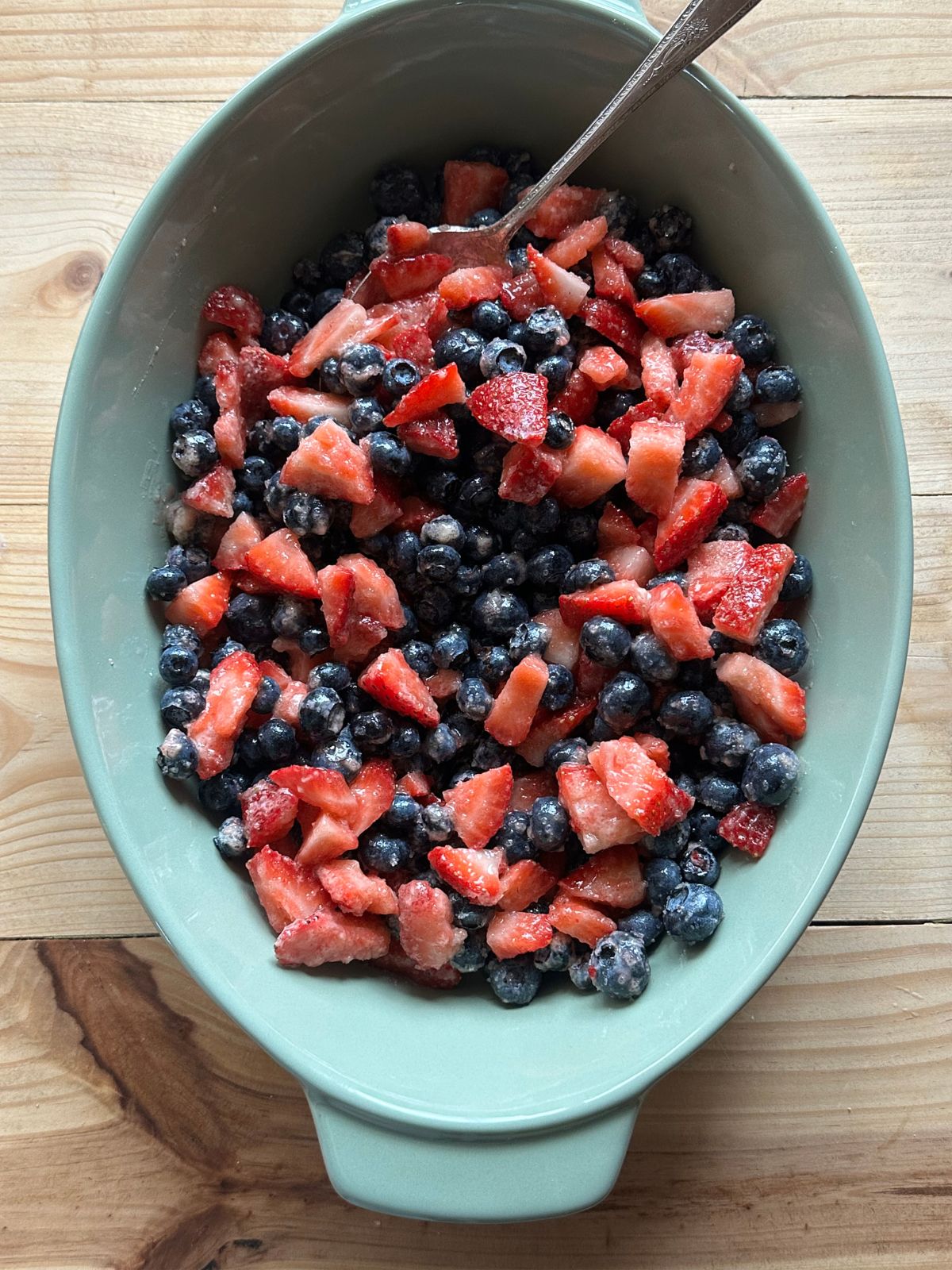 chopped strawberries and blueberries tossed together in a large green baking dish