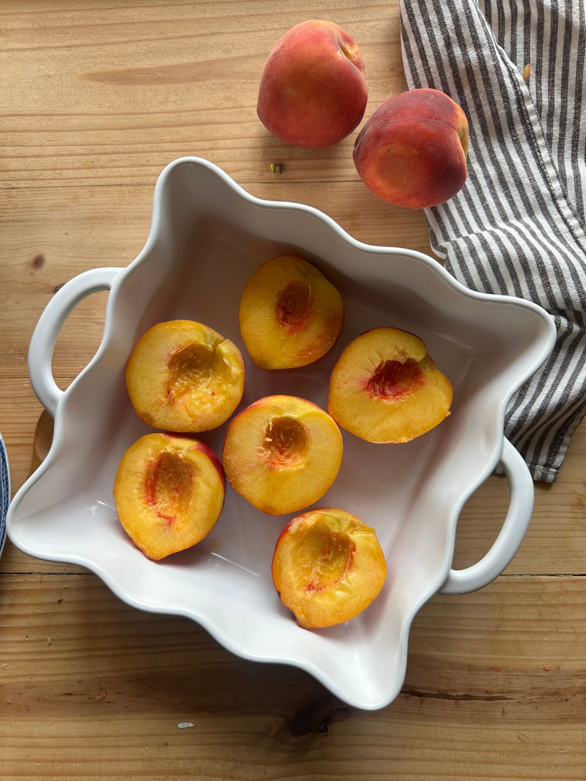 sliced peaches arranged in a white baking dish