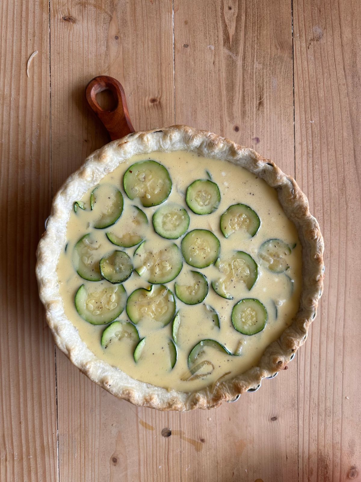 unbaked quiche on a wooden countertop