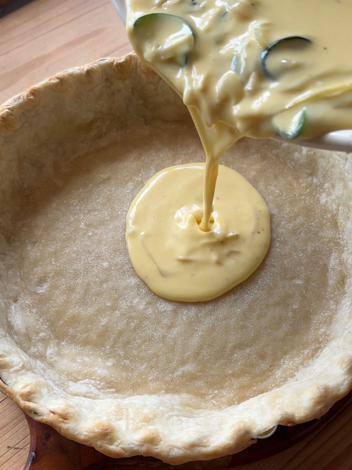 custard filling for quiche being poured into a pie crust