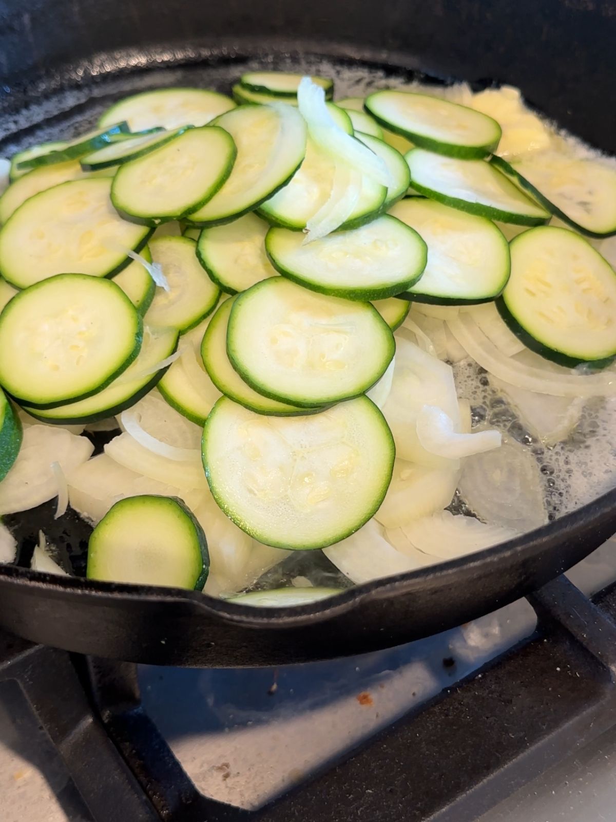a pile of sliced zucchini and onion in a cast iron skillet