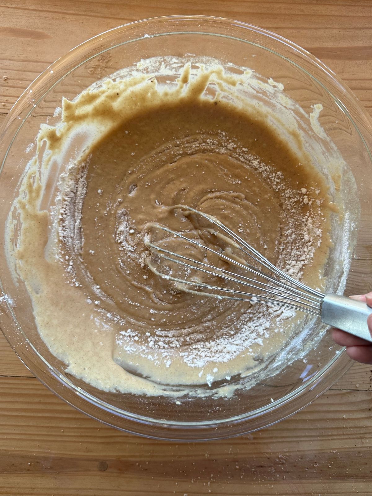 apple cider donut batter being whisked together in a large glass mixing bowl