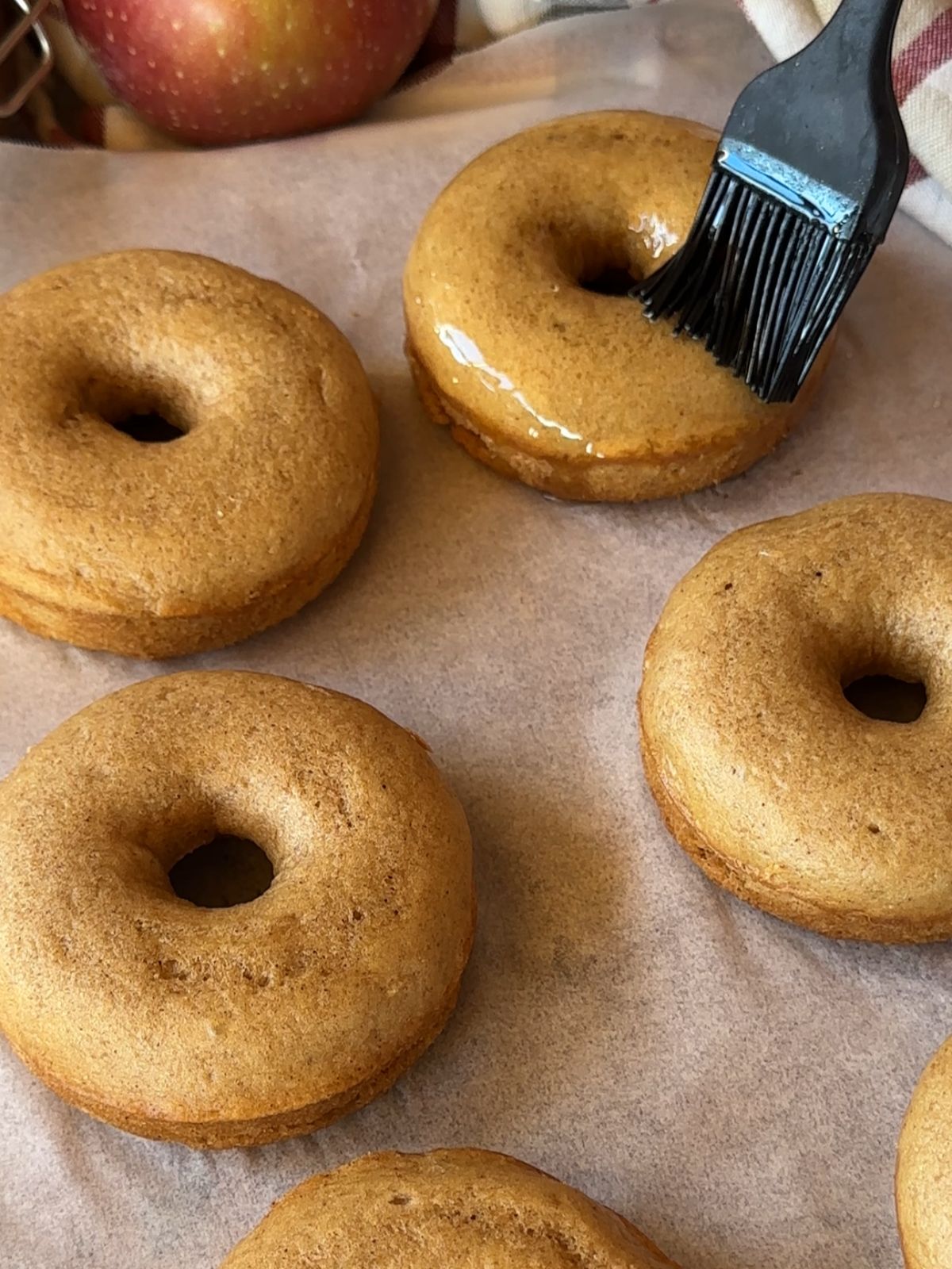 baked apple cider donuts being brushed with melted butter